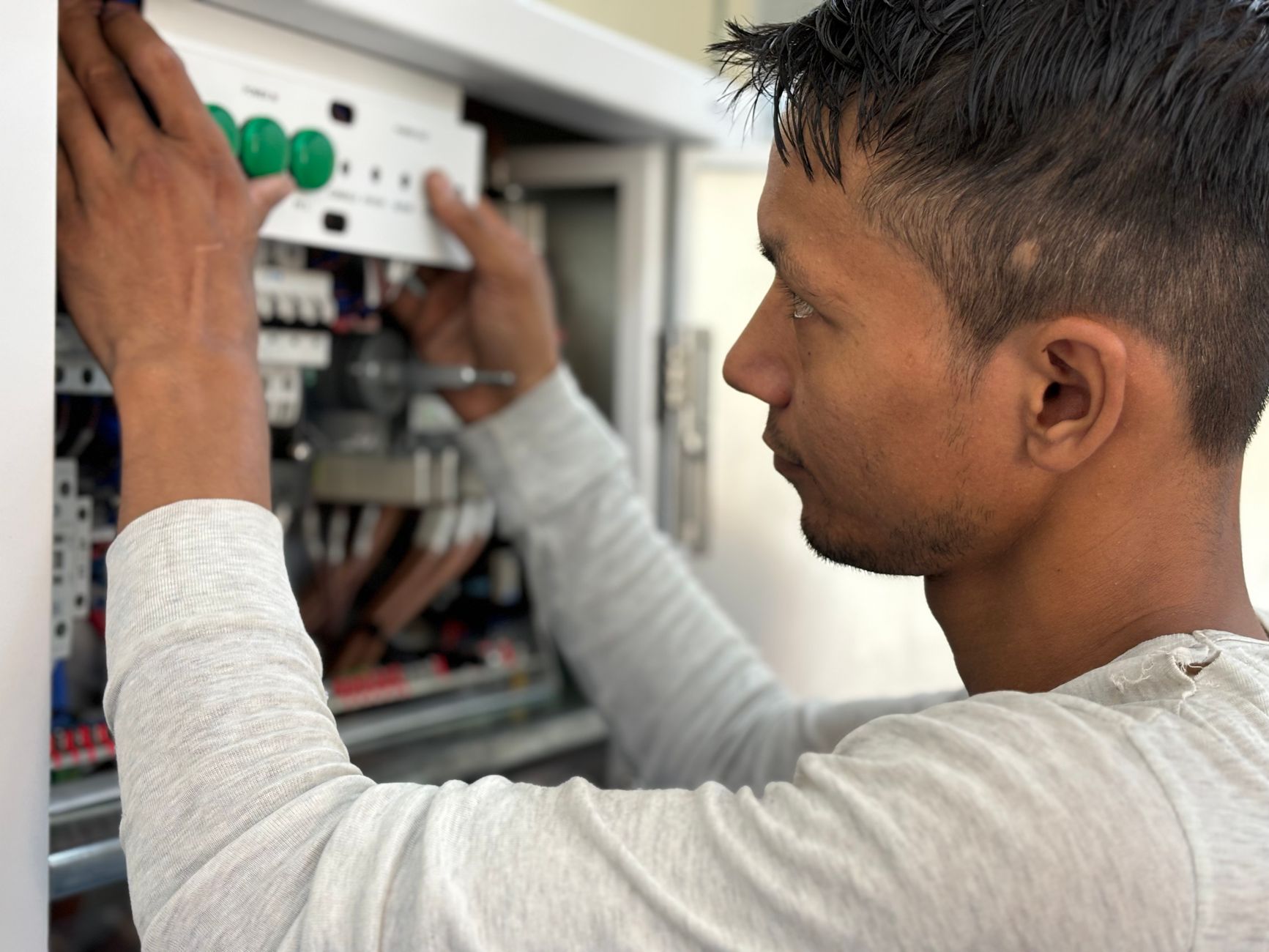 Electrician working beside a modern consumer unit in a tidy home interior